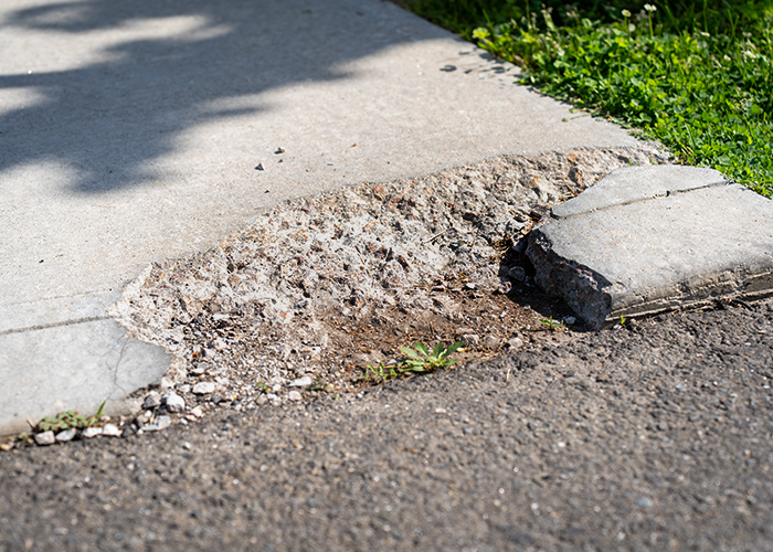 Chipped up and broken concrete sidewallk.